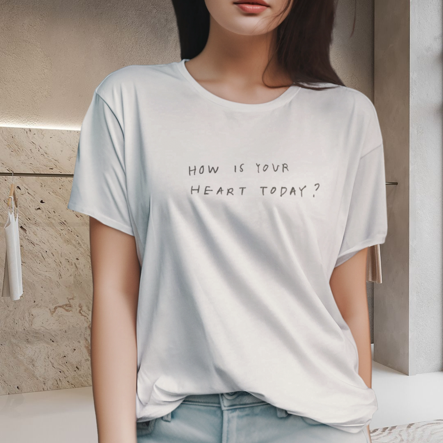 t-shirt with raw minimalist had written quote 'how is your heart today' black color  100% cotton white color wore by a female european model brunette high body angle of view on an minimalist interior background changing room