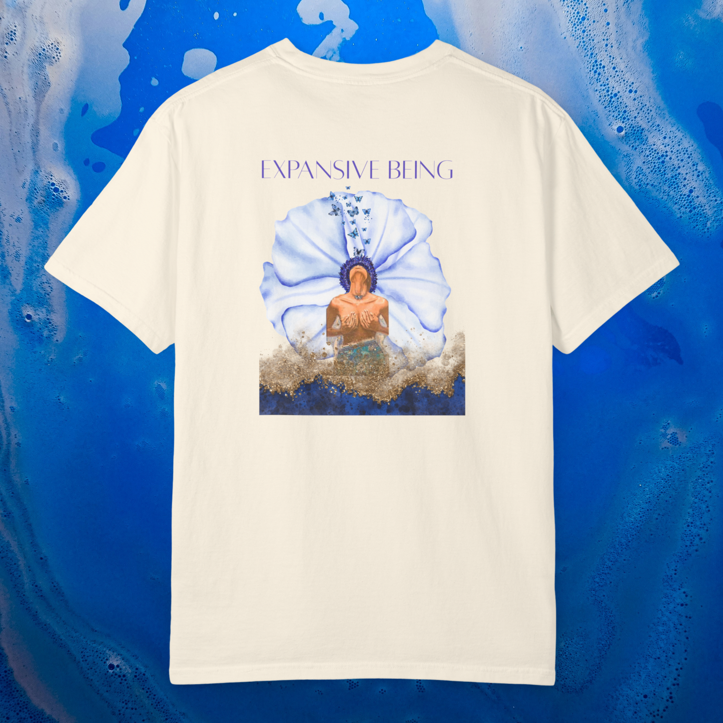 a white ivory color t-shirt spiritually designed to heal the throat chakra the design graphic is a women in a blue flower she breathe out butterflies the color is blue gold ligh blue and orange the t-shirt is 100% cotton premium quality high vibrational clothing line. the background is ocean blue soft